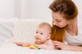 Mother and child on a white bed. Mom and baby boy in diaper playing in sunny bedroom. Royalty Free Stock Photo