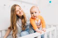 Mother and child on a white bed. Mom and baby boy are playing. A parent and a small child are resting at home. Family has fun Royalty Free Stock Photo