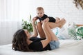 Charming happy little baby boy having fun with mom brunette woman on bed in the bright bedroom Royalty Free Stock Photo