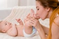 Mother and child on a white bed. Mom and baby girl in diaper playing in sunny bedroom. Royalty Free Stock Photo