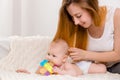 Mother and child on a white bed. Mom and baby girl in diaper playing in sunny bedroom. Royalty Free Stock Photo