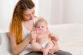 Mother and child on a white bed. Mom and baby girl in diaper playing in sunny bedroom. Royalty Free Stock Photo