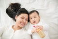 Mother and child on a white bed. Mom and baby girl playing. Parent and little kid relaxing at home. Family having fun together. Be Royalty Free Stock Photo