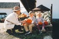Mother with children are choosing pumpkin in farm market. Woman and little kids playing on fall walk at countryside. Thanksgiving