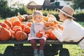 Mother with children are choosing pumpkin in farm market. Woman and little kids playing on fall walk at countryside. Thanksgiving