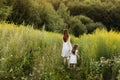 Mother with daughter walking along a country road, background summer meadow sunset, back view Royalty Free Stock Photo