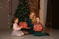 Mother and children exchanging and opening Christmas presents.