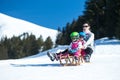 Mother and children having fun on sledge with panoramatic view of Alps mountains. Active mom and toddler kid with safety helmet. Royalty Free Stock Photo