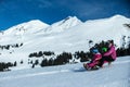 Mother and children having fun on sledge with panoramatic view of Alps mountains. Active mom and toddler kid with safety helmet. Royalty Free Stock Photo