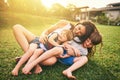 Mother, children and hug playing on grass for fun bonding in the sun outside their house in nature. Happy mom hugging Royalty Free Stock Photo