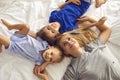 Mother and children are lying smiling hugging on the bed in the room. Mothers Day.