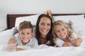 Mother and children lying together on bed in bedroom at home Royalty Free Stock Photo