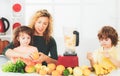 Mother with children making smoothie in a white kitchen. Family mother and child daughter and son blended smoothie with Royalty Free Stock Photo