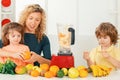 Mother with children making smoothie in a white kitchen. Family mother and child daughter and son blended smoothie with Royalty Free Stock Photo