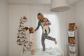 Mother and children in pajamas jumping on the bed in the morning Royalty Free Stock Photo