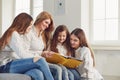 Mother with children reads a book while sitting on a sofa in a room. Royalty Free Stock Photo