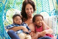 Mother With Children Relaxing On Outdoor Garden Swing Seat Royalty Free Stock Photo