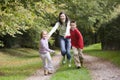 Mother and children running along woodland path Royalty Free Stock Photo