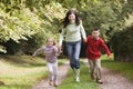 Mother and children running along woodland path Royalty Free Stock Photo