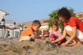 Mother with children sits on beach in day-time Royalty Free Stock Photo