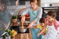 Mother and children together making apple pie in the kitchen at home. Children helping mother Royalty Free Stock Photo