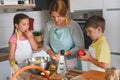 Mother and children together making apple pie in the kitchen at home. Children helping mother Royalty Free Stock Photo