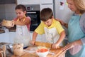 Mother and children together making apple pie in the kitchen at home. Children helping mother Royalty Free Stock Photo