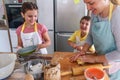 Mother and children together making apple pie in the kitchen at home. Children helping mother Royalty Free Stock Photo