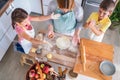 Mother and children together making apple pie in the kitchen at home. Children helping mother Royalty Free Stock Photo