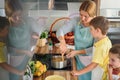 Mother and children together making apple pie in the kitchen at home. Children helping mother Royalty Free Stock Photo