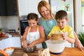 Mother and children together making apple pie in the kitchen at home. Children helping mother Royalty Free Stock Photo