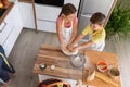 Mother and children together making apple pie in the kitchen at home. Children helping mother Royalty Free Stock Photo