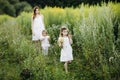 Mother with children two daughters walking along a country road, background summer meadow sunset, back view Royalty Free Stock Photo