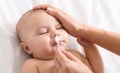 Mother cleaning baby nose with cotton swab