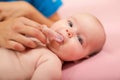 Mother cleaning baby`s mouth with special fingertip brush