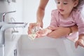 Mother cleaning kids hands with sanitizer liquid soap after baby toddler had dirty fingers in the sink. Healthy