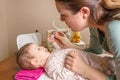 Mother cleaning mucus of baby with nasal aspirator