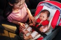 mother consoling newborn baby crying while putting and fasten seat belts on car seat Royalty Free Stock Photo
