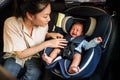 mother consoling newborn baby crying while putting and fasten seat belts on car seat Royalty Free Stock Photo