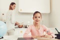 Mother Cooks On Kitchen. Daughter Does Homework. Royalty Free Stock Photo