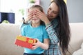 Mother covering her daughter eyes with her hands. Little girl holding box with gift Royalty Free Stock Photo