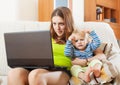 Mother with crying baby working with laptop