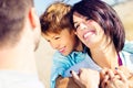 Mother cuddles her son while father watches them moved