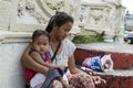Mother cuddling baby son at church yard patio selling candles