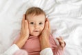 Mother cuddling with cute little baby girl, touching kid cheeks, lying ob bed, top view, free space Royalty Free Stock Photo