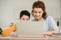 Mother with cute son using laptop together while doing schoolwork at home Royalty Free Stock Photo