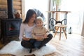 Mother and cute toddler child in a little fancy wooden cottage, reading a book, drinking tea