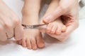 Mother cutting fingernails on the feet of her child using nail scissors. Royalty Free Stock Photo