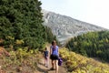 A mother and daugher hiking a beautiful trail above the treeline with a huge mountain in the background during a sunny fall day