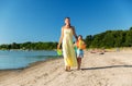 Mother and daughter with ball walking along beach Royalty Free Stock Photo